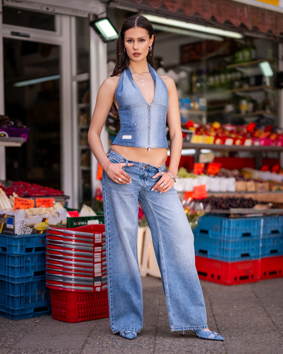 Model trägt das Waisted-Talent-Korsett zu weiter Jeans vor einem Obst- und Gemüseladen